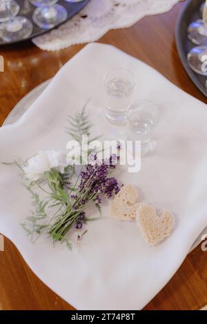 Tema del matrimonio. Bicchieri di cristallo con alcool, dolci sono posti su tovagliolo di lino bianco-neve. Foto Stock