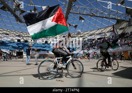 Gli yemeniti tengono in mano bandiere palestinesi, ballano e cavalcano una bicicletta durante una veglia per mostrare solidarietà al popolo palestinese, a Sana'a, Yemen, il 13 novembre 2023. Migliaia di israeliani e palestinesi sono morti da quando il gruppo militante Hamas ha lanciato un attacco senza precedenti contro Israele dalla Striscia di Gaza il 7 ottobre e gli scioperi israeliani sull'enclave palestinese. Foto Stock