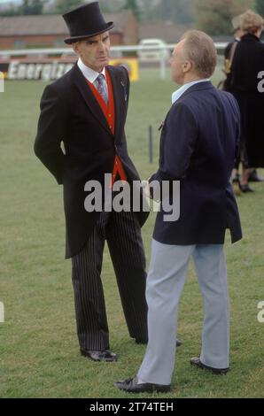 Stile a contrasto e classe sociale due uomini amici Inghilterra anni '1980. Derby Day, un uomo vestito in modo informale e intelligente, un altro abbigliamento formale da uomo è richiesto un top in seta nera e un cappotto di coda. Epsom Downs, Surrey Inghilterra Regno Unito 1985 HOMER SYKES Foto Stock