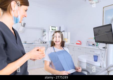 Dentista femminile che mostra i denti modello paziente sorridente Foto Stock