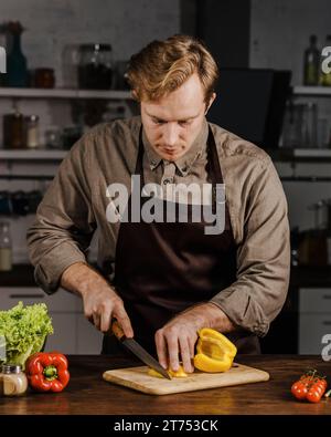 Lo chef medio affetta i peperoni Foto Stock