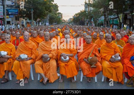 Molti monaci thailandesi meditano durante la tradizionale cerimonia di consegna delle elemosine buddiste la mattina presto. Raduno annuale di 10.000 monaci buddisti. Foto Stock