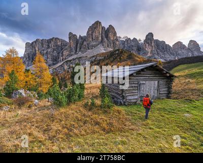 Escursionista di fronte al rifugio e gruppo del Sella, passo Gardena, autunno, gruppo del Sella, Dolomiti, Bolzano, alto Adige Foto Stock