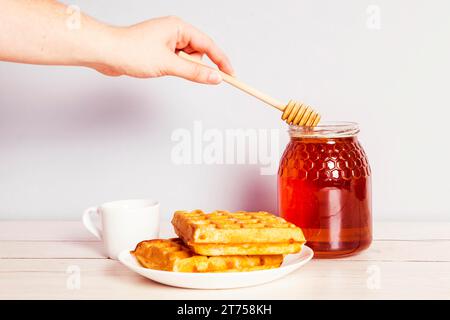 Mano della persona con la raccolta del miele dal barattolo per la colazione Foto Stock
