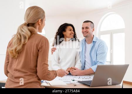 Felice ha abbracciato la coppia conversando con un agente immobiliare femminile Foto Stock