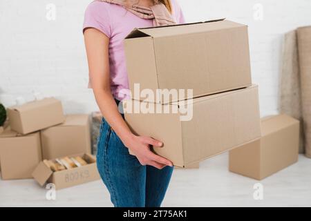 Giovane donna con sezione centrale che regge scatole di cartone impilate Foto Stock