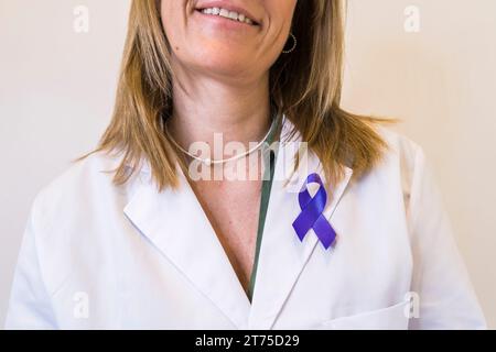 Primo piano del nastro viola fissato sul camice bianco da laboratorio della dottoressa. Foto Stock