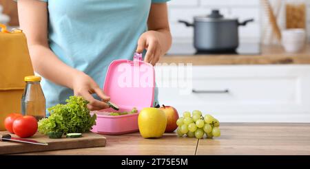 Donna che confeziona cibo fresco nel cestino per il pranzo in cucina Foto Stock