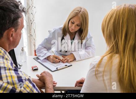 Medico donna che scrive prescrizione medica a un paio Foto Stock
