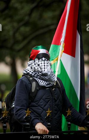 Austin, Texas, USA. 13 novembre 2023. Un manifestante che indossa i colori della bandiera palestinese ascolta gli oratori sul terreno del Campidoglio del Texas ad Austin, Texas, il 12 novembre. Era uno dei migliaia che conversero lì per chiedere un immediato cessate il fuoco dell'assedio israeliano di Gaza ora al suo secondo mese. Undici mila civili sono stati uccisi finora. (Immagine di credito: © Jaime Carrero/ZUMA Press Wire) SOLO USO EDITORIALE! Non per USO commerciale! Foto Stock