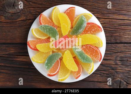 Marmellata a forma di fette di agrumi su un piatto su sfondo di legno, vista dall'alto Foto Stock