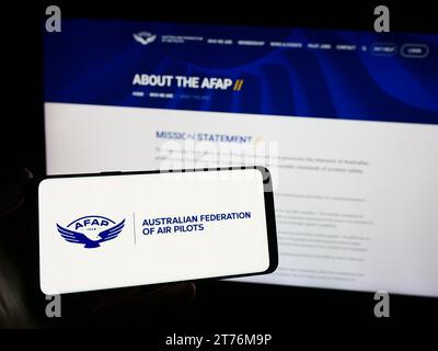 Persona che possiede uno smartphone con il logo dell'associazione Australian Federation of Air Pilots (AFAP) davanti al sito Web. Concentrarsi sul display del telefono. Foto Stock