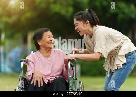 felice giovane nipote che parla con una donna anziana in sedia a rotelle al parco Foto Stock