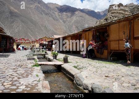Bancarelle con canali d'acqua e montagne dietro. Ollantaytambo, Perù, 5 ottobre 2023. Foto Stock