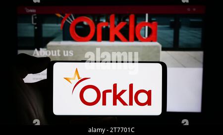 Persona che possiede uno smartphone con il logo della società norvegese Orkla ASA davanti al sito Web. Concentrarsi sul display del telefono. Foto Stock