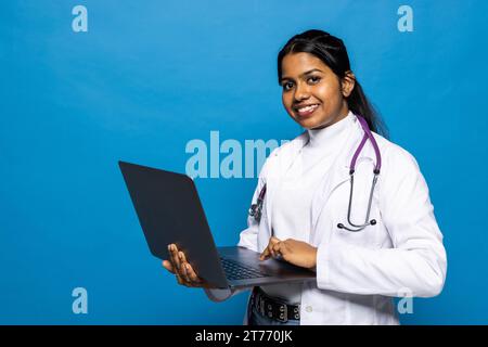 Attraente medico indiano che pongono la donna in uno studio di fronte a uno sfondo Foto Stock