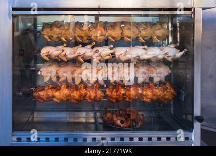 Una pila di pollo grigliato su uno spiedino fritto in un forno commerciale. Arrostimento di pollo nel forno a rosticceria commerciale. Arrostire il pollo nel forno. Foto Stock