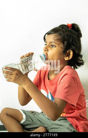 Una ragazza carina che beve acqua in studio per fotografare Foto Stock