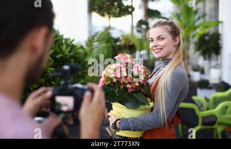 Felice Vlogger posa con fiore all uomo della fotocamera Foto Stock