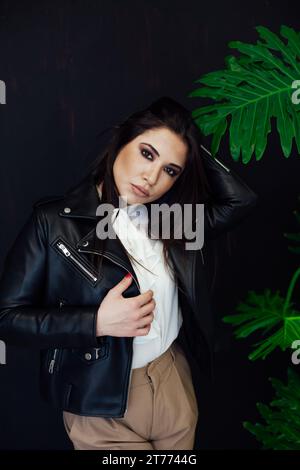 bruna donna vicino a una pianta verde in una serra Foto Stock