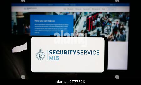 Persona che possiede uno smartphone con il logo dell'agenzia britannica di controspionaggio Security Service (MI5) davanti al sito web. Concentrarsi sul display del telefono. Foto Stock