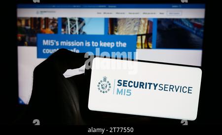 Persona che possiede un telefono cellulare con il logo dell'agenzia britannica di controspionaggio Security Service (MI5) davanti alla pagina web. Concentrarsi sul display del telefono. Foto Stock