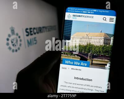 Persona in possesso di cellulare con pagina web dell'agenzia britannica di controspionaggio Security Service (MI5) con logo. Concentrarsi sul centro del display del telefono. Foto Stock