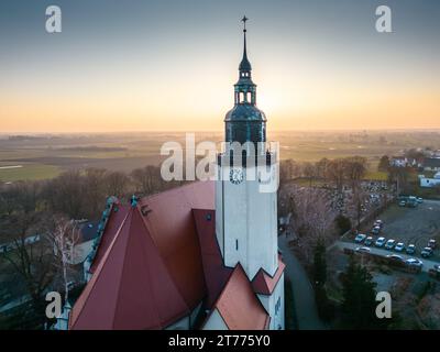 Questa vista aerea cattura una pittoresca scena invernale di una chiesa circondata dai suoi idilliaci terreni innevati Foto Stock