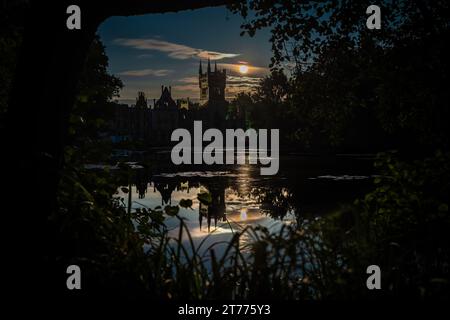 Questa immagine mostra un paesaggio urbano notturno che si affaccia su un lago tranquillo, con edifici sagomati sullo sfondo Foto Stock