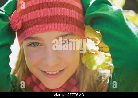 Giovane ragazza sorridente con le mani sulla testa indossando un cappello di lana Foto Stock