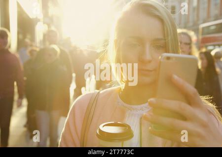 Giovane donna utilizza lo smartphone sulla strada di città Foto Stock