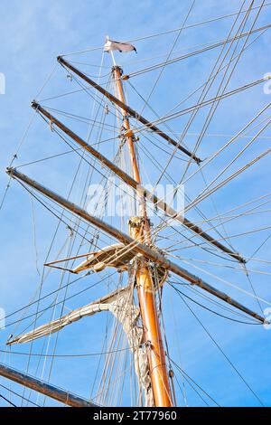 vista verso l'alto degli alberi di una nave sul cielo blu Foto Stock