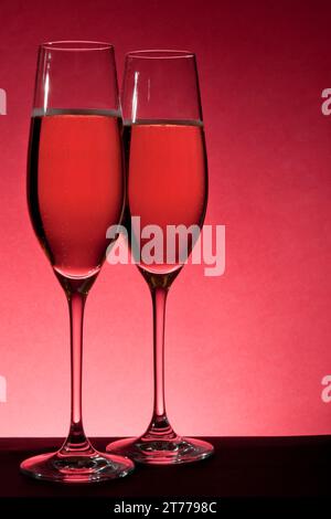 due bicchieri completi di champagne su sfondo rosso Foto Stock