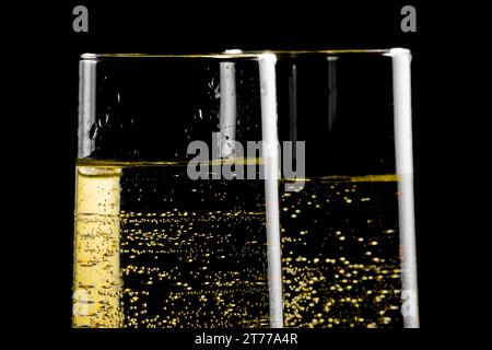 dettaglio di un paio di flute di champagne con bolle d'oro su sfondo nero Foto Stock