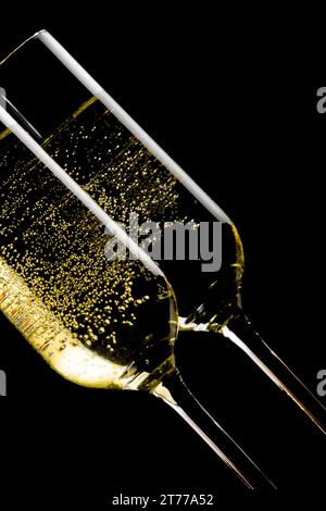 dettaglio di un paio di flauti inclinati di champagne con bolle d'oro su sfondo nero Foto Stock