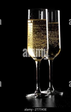 un paio di flauti di champagne con bolle d'oro su sfondo di legno nero e spazio per il testo Foto Stock