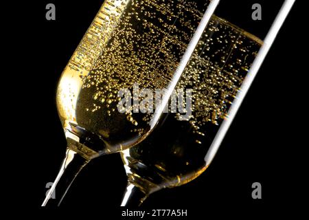 dettaglio di un paio di flute di champagne con bolle d'oro su sfondo nero Foto Stock