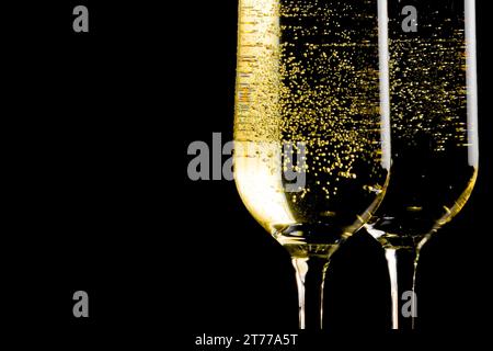 un paio di flute di champagne con bolle d'oro su sfondo nero e spazio per il testo Foto Stock
