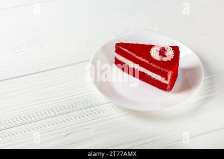 Torta di velluto rosso a una fetta su piatto bianco su tavolo di legno Foto Stock