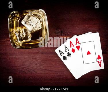 vista dall'alto delle carte da gioco a poker vicino al vetro della sciabola sul vecchio tavolo di legno Foto Stock