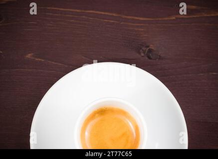 vista dall'alto di mezza tazza di caffè espresso italiano su un vecchio tavolo in legno con spazio per il testo Foto Stock