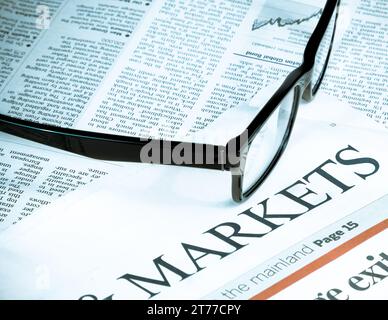 occhiali da vista neri vicino ai mercati di parole su giornali finanziari, business e concetto finanziario Foto Stock