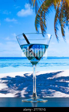 cocktail blu sulla spiaggia e tavolo in legno, mare blu e sfondo cielo Foto Stock