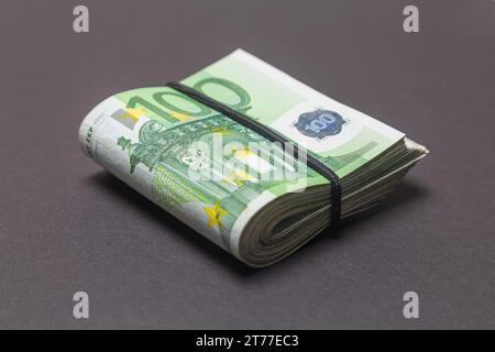 Un pacchetto di 100 banconote IN EURO piegate a metà su sfondo scuro. Foto Stock