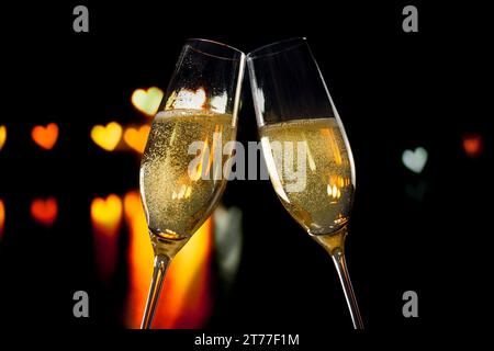 flauti di champagne con bollicine dorate fanno il tifo su uno sfondo bokeh di san valentino Foto Stock