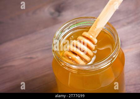 vasetto di miele su tavolo in legno con cucchiaia in legno di miele sulla parte superiore Foto Stock