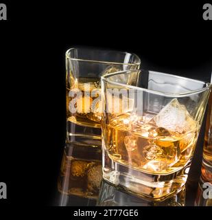 whisky con ghiaccio nei bicchieri vicino al flacone su sfondo nero, con riflesso Foto Stock