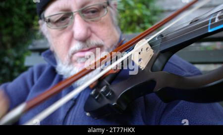 Un anziano che suona un violino elettrico Foto Stock