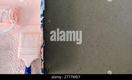 Sul tavolo è presente un vassoio di verniciatura, con vernice, un rullo e una spazzola in vernice su un tavolo grigio Foto Stock