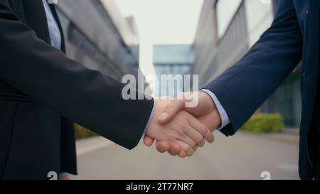 Saluto formale affari stretta di mano città all'aperto edificio di uffici urbano primo piano mani uomo donna handshake accordo di partnership affare di successo femminile Foto Stock